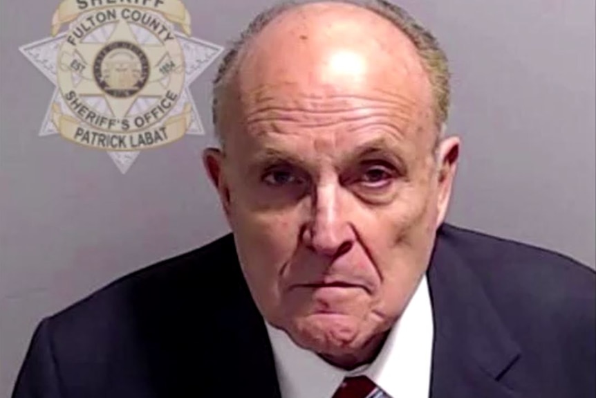 A old man in a mugshot wearing a suit with a flag 