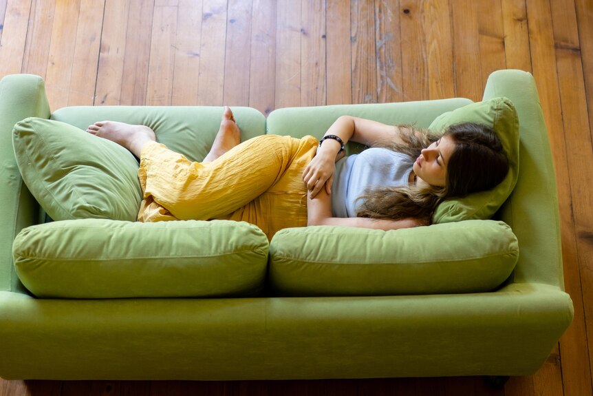 A woman lies on a green couch