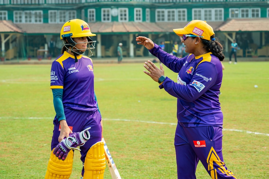 Coach Anju Jain passes on some advice to a young female player on the cricket field.