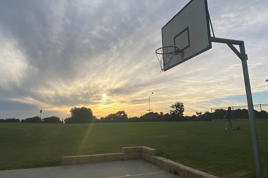 A photo of a basketball court at sunset. 