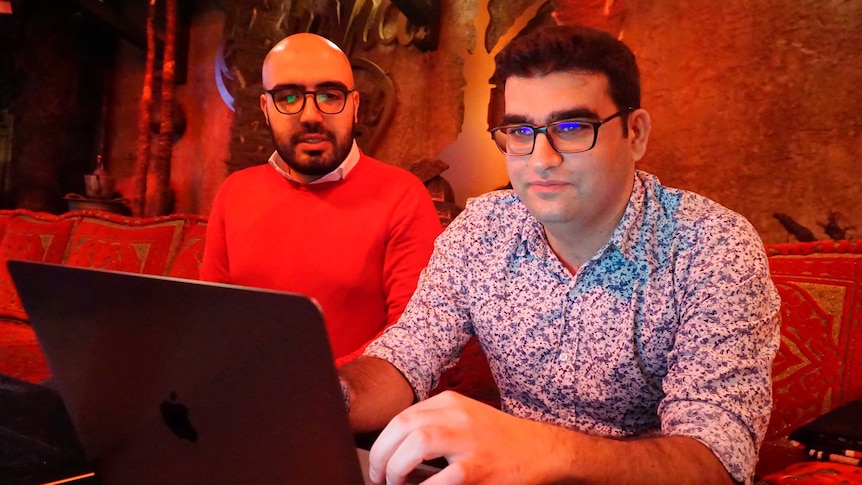 Certfa researchers sit at a computer in a red lit room