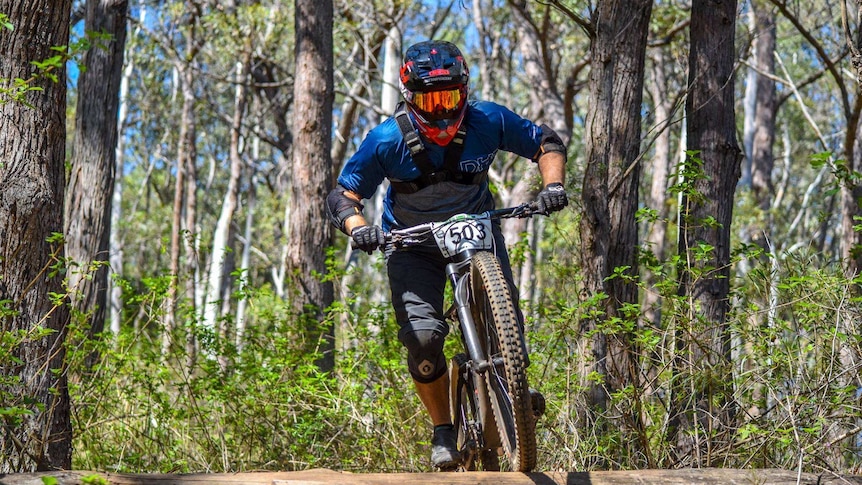 A mountain bike rider rides along a bush track.