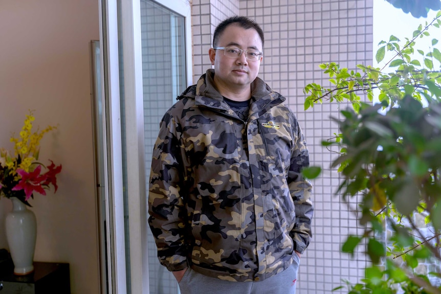 A wideshot of a man standing on his balcony at home.