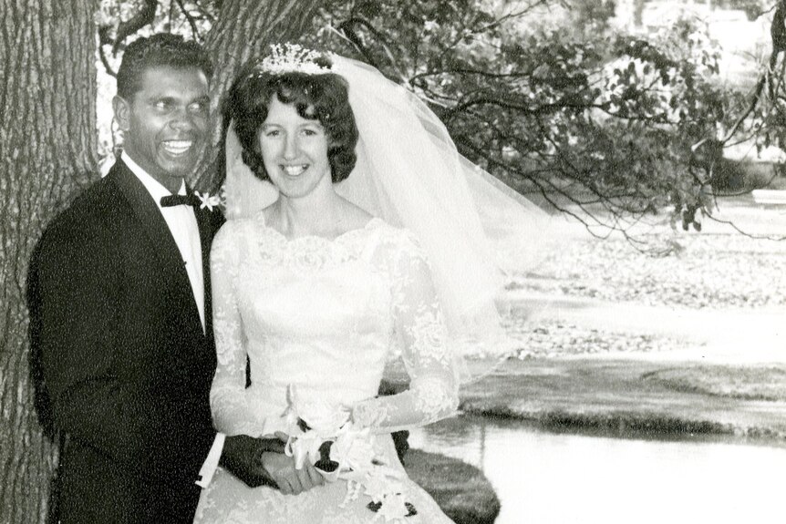 A black and white photo of Cedric and Narelda, dressed in a suit and wedding gown, smiling, on their wedding day