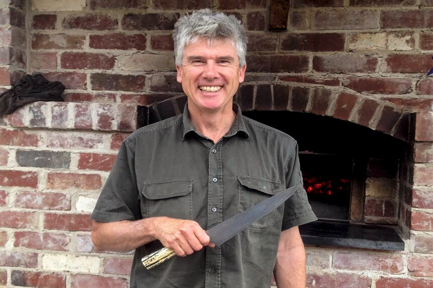 Chef Matthew Evans standing in front of a pizza oven outside with his knife