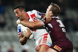 A St George Illawarra NRL player carries the ball with his right hand as he is tackled by a Manly opponent.
