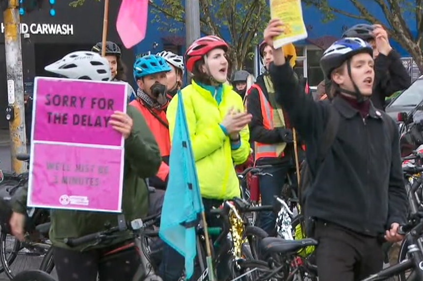 Extinction Rebellion protesters on bikes and holding signs on Hoddle St.