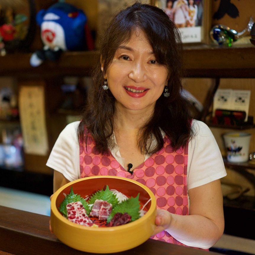 A lady holding a bowl of whale meat
