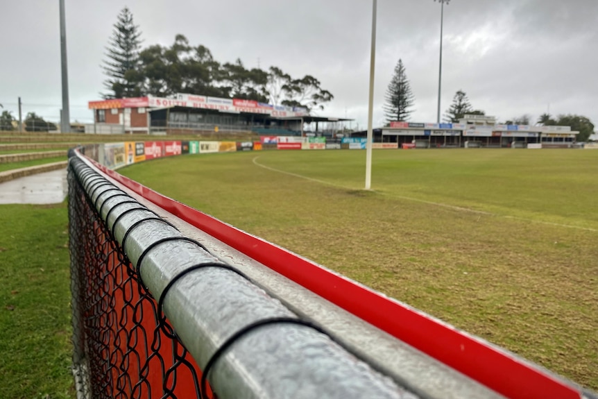 The boundary fence running alongside a football oval