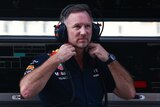 Christian Horner looks into the distance holding his collar wearing a headset