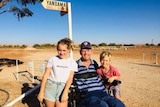 A man in his wheelchair with his daughter and son standing beside him