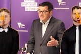 A composite of Premier Daniel Andrews in a suit at a press conference podium, flanked by DJs Mashd N Kutcher
