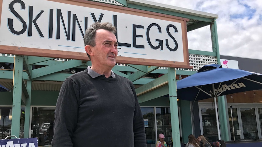 Tim Carroll stands outside a shopfront and looks off camera