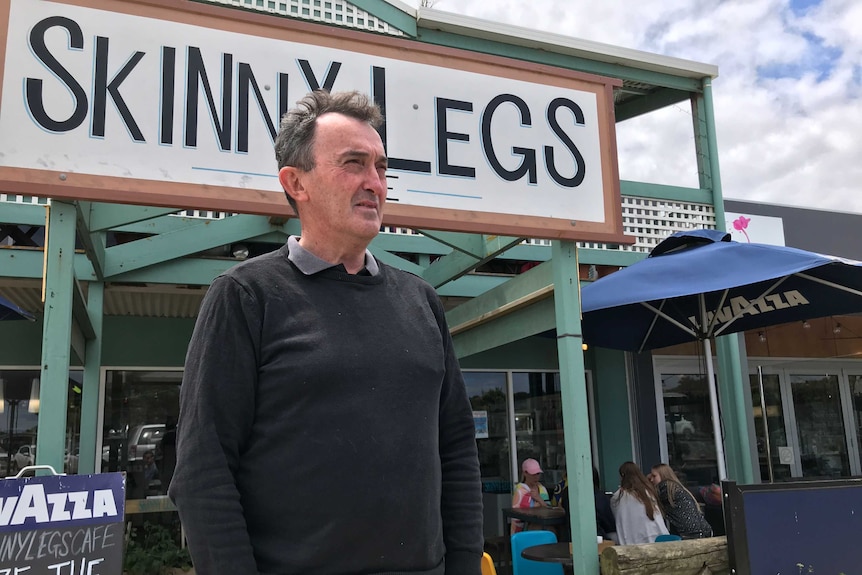 Tim Carroll stands outside a shopfront and looks off camera