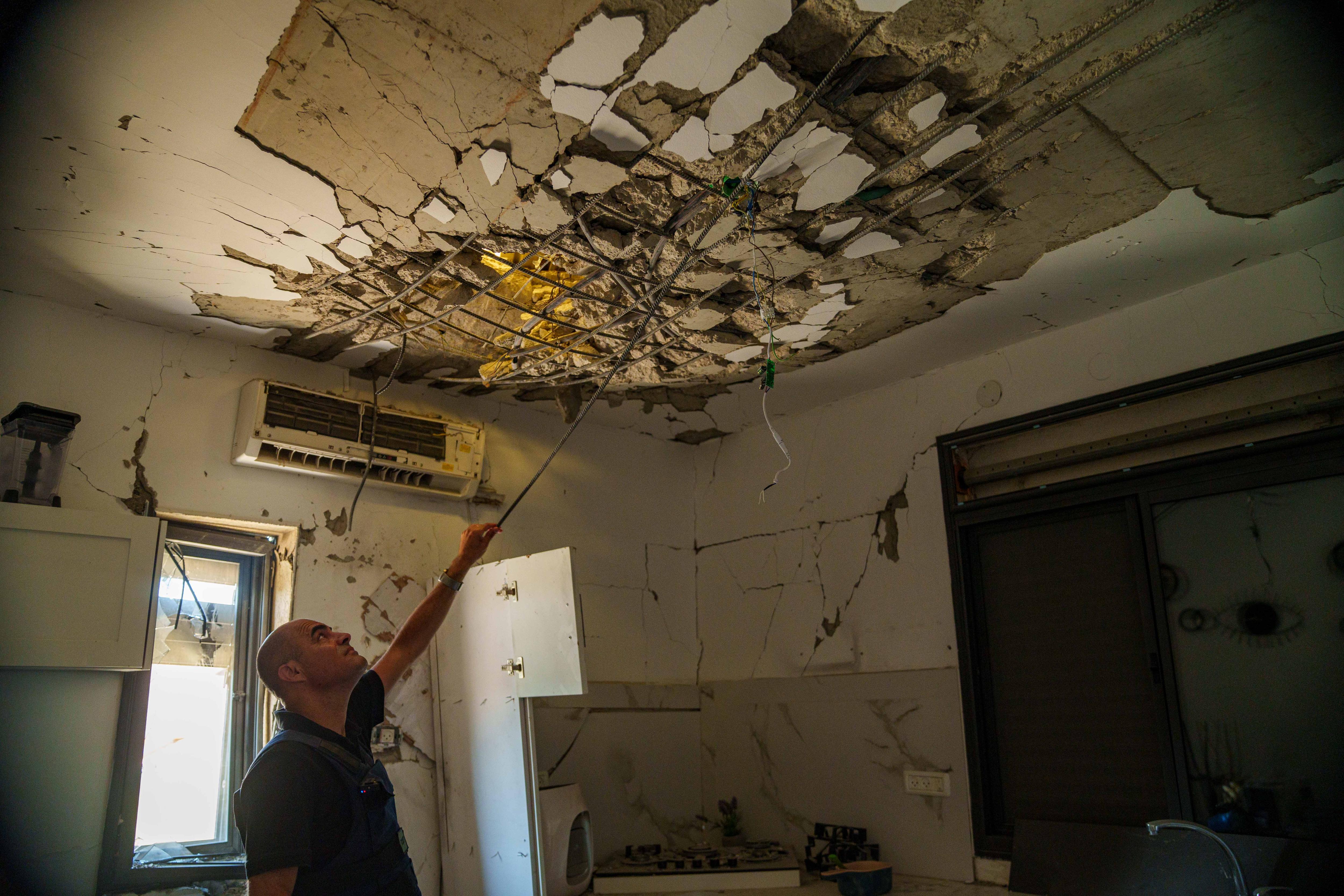 A man investigates the damage in a ceiling 