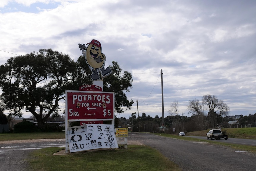 Country road in western Victoria with ute and roadside potato shop on the left 