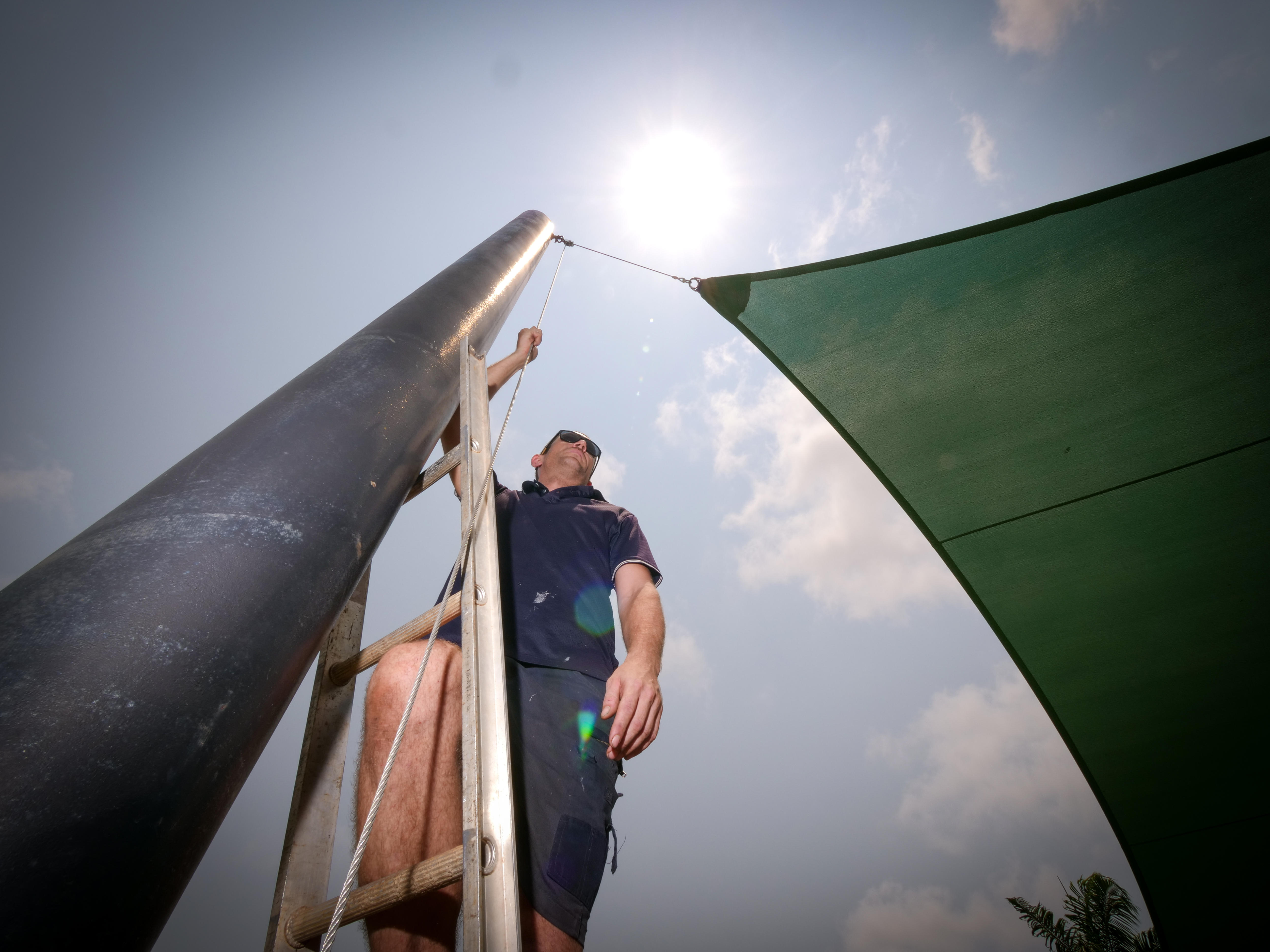 Shade sail worker Kane McLatchie works outside during a heatwave