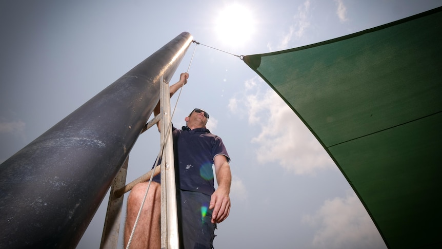 Shade sail worker Kane McLatchie works outside during a heatwave