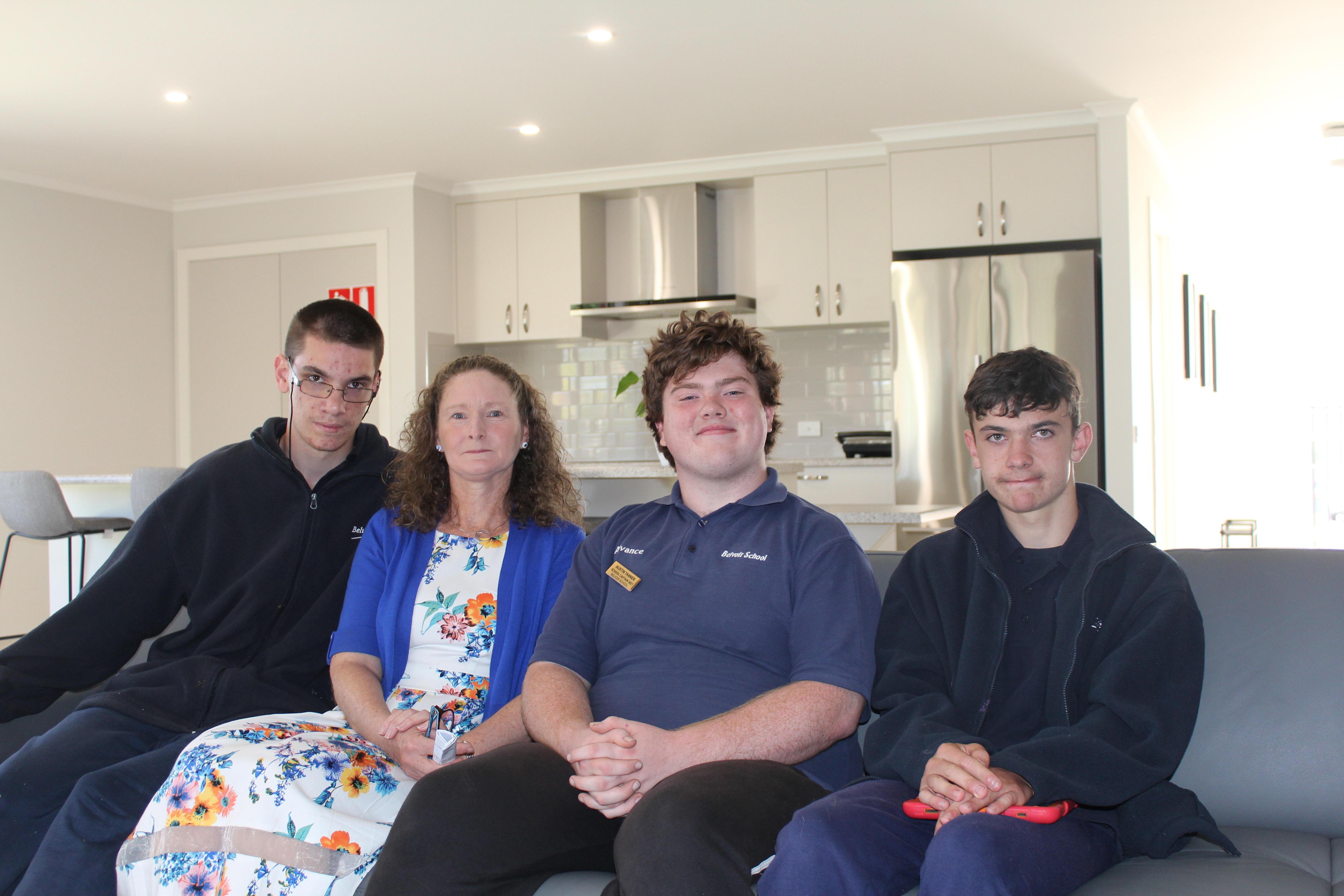 Four people sitting on a couch inside the house.