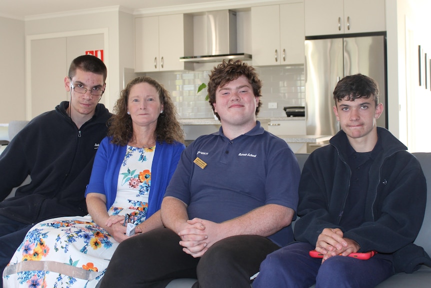 Four people sitting on a couch inside the house.