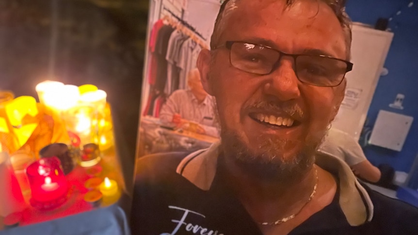 A photo of a man in glasses next to candles