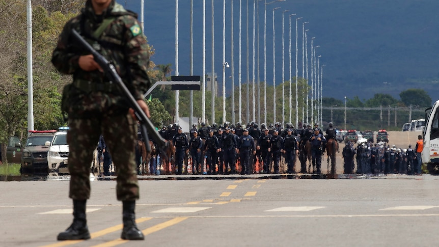 Soldiers and police stand watch as supporters of former Brazilian President Jair Bolsonaro depart their encampment.