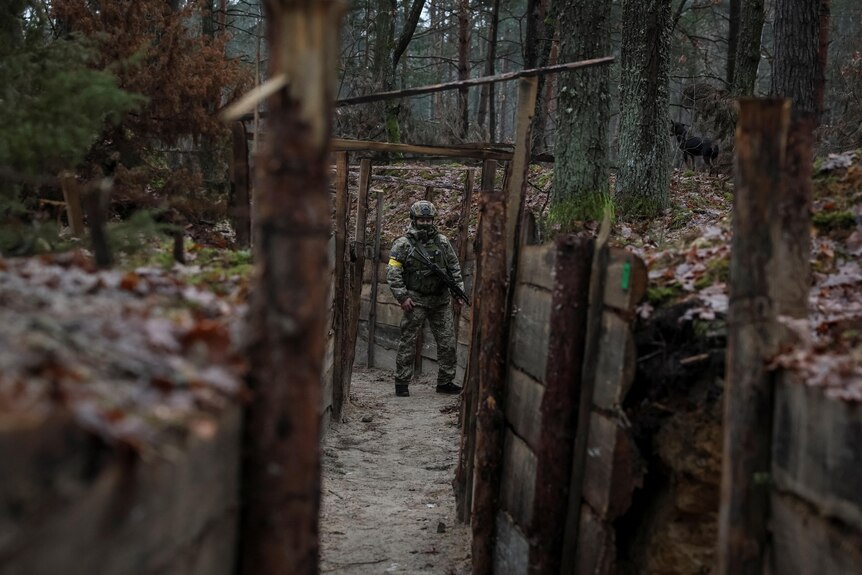 A soldier walks in a trench in Ukraine near Belarus.
