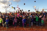 A large group of parents and school students throwing their hats in the air after a school camp.