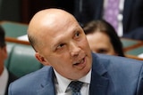 Peter Dutton cocks his head to one side to look upwards.