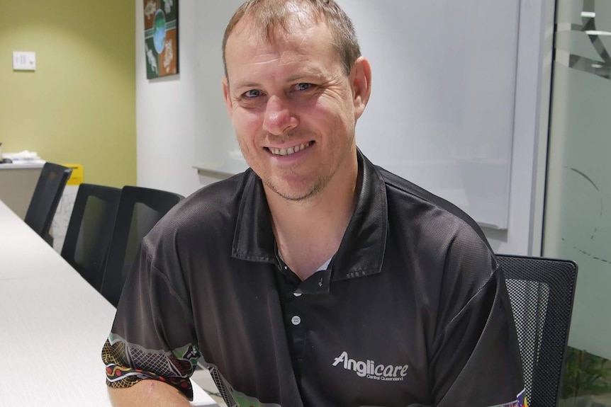 A caucasian man in an office smiles at the camera.