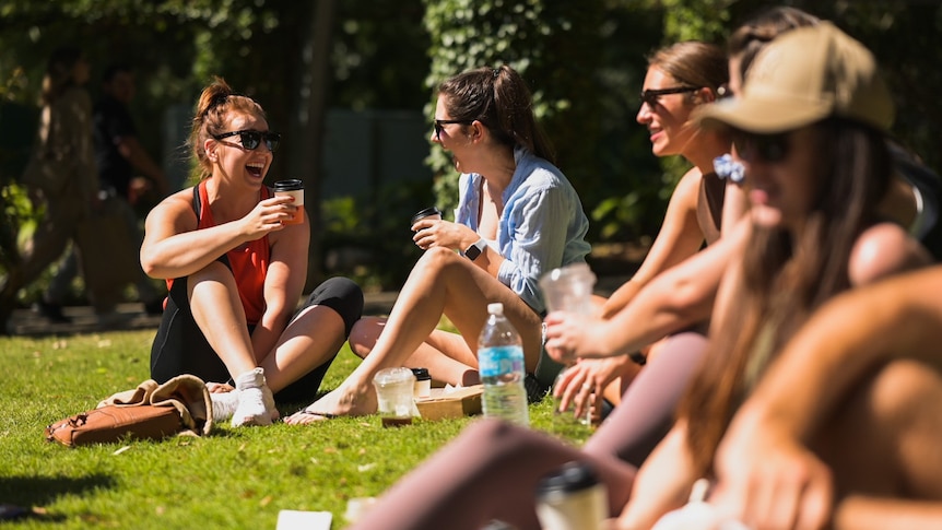 A group of people sitting in the sun and drinking coffee