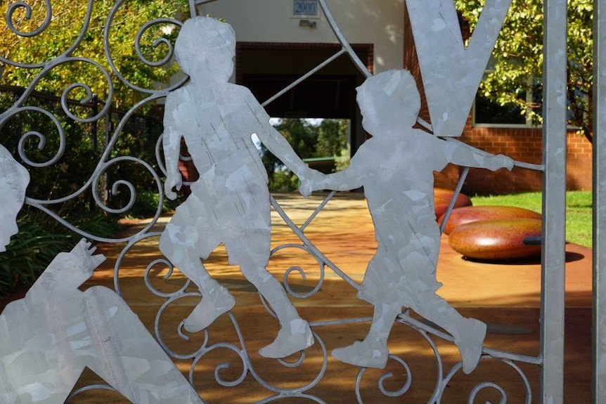 A wrought iron gate outside Wembley Primary School with the outlines of two children on it.