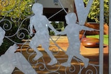 A wrought iron gate outside Wembley Primary School with the outlines of two children on it.