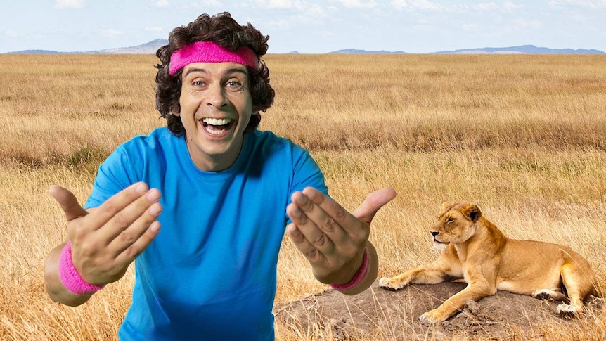 Andy wearing a headband and wristbands standing in front of a lion