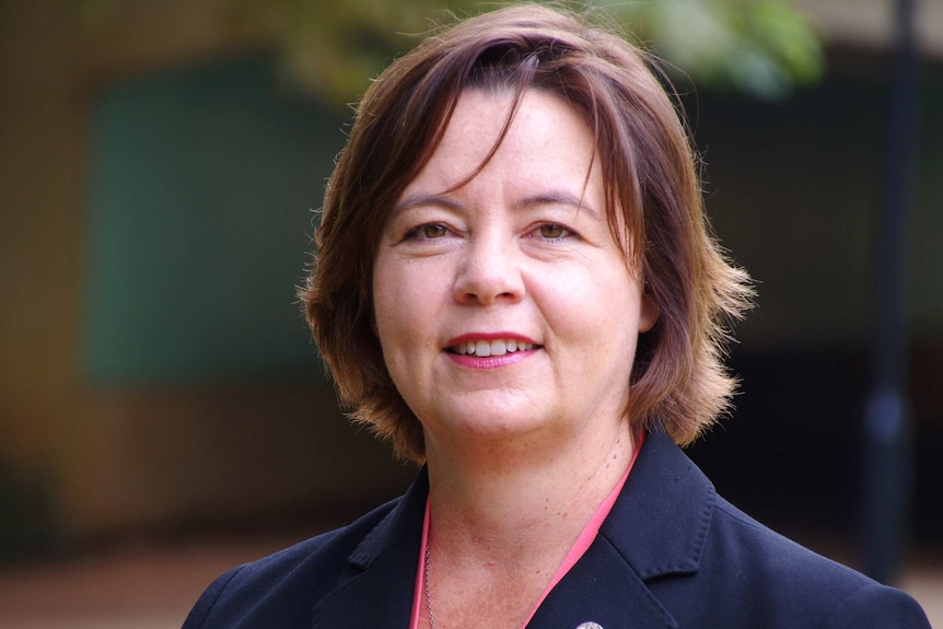 Caucasian woman with brown shoulder length hair, wearing suit jacket and shirt