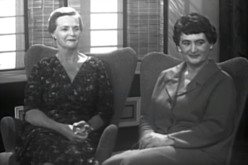 Still from black and white video footage: Jean Inkster and Tony Tompson sit in matching armchairs looking at their host.