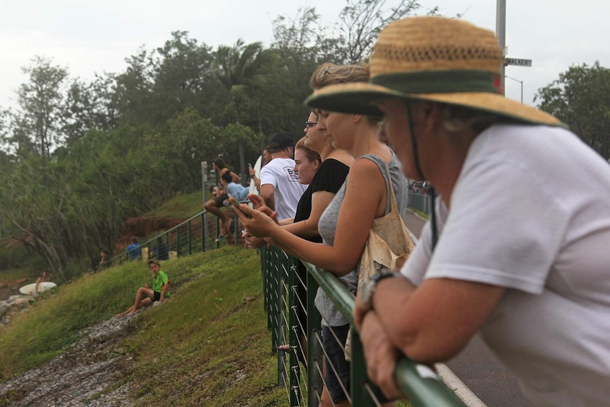 A group of spectators lining a footpath watching the surfers.