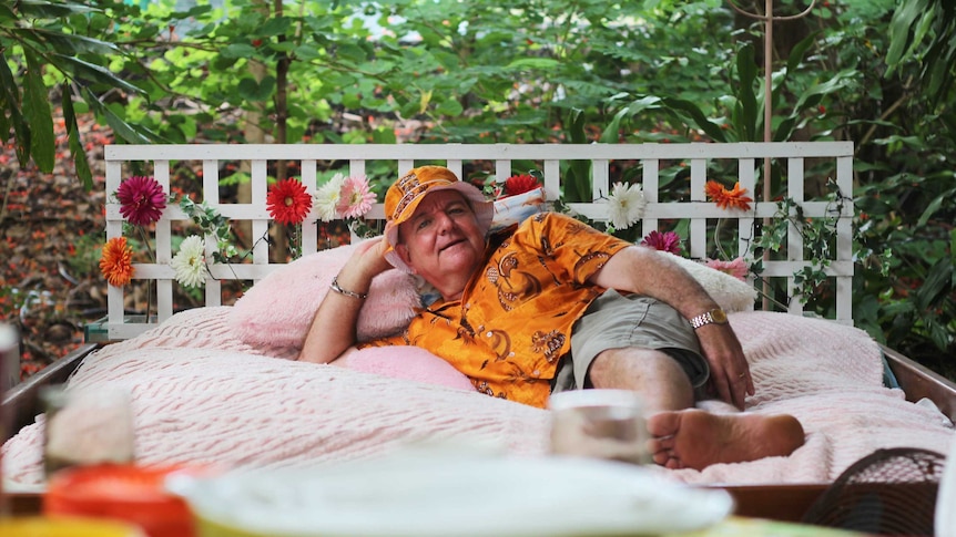 A man in a colourful outfit in a kitsch bed