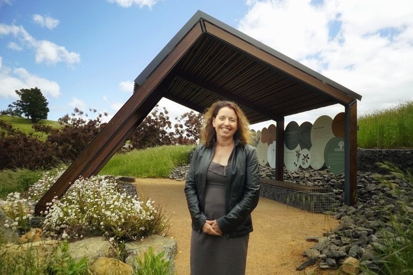 A woman in a leather jacket stands outside in a leather jacket.