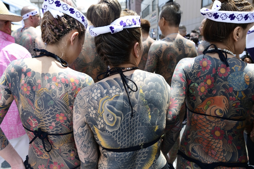 Heavily tattooed Japanese women chat in the street at the Sanja Festival on the streets of Asakusa.
