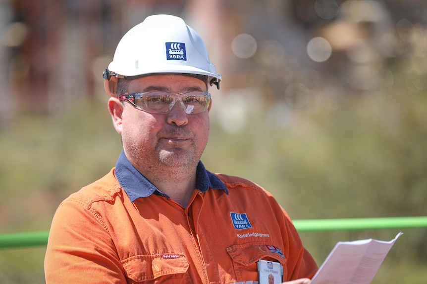 A man in high viz, a hard hat and safety glasses.