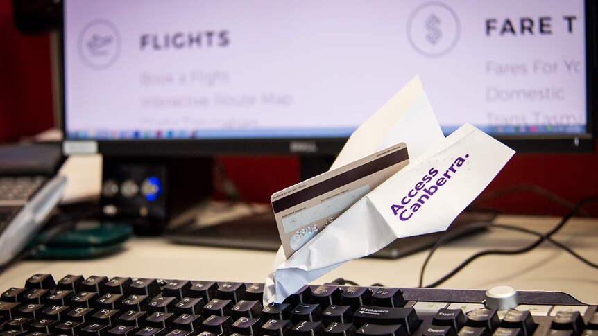 An Access Canberra paper plane with a credit card in it, crashed into a keyboard.