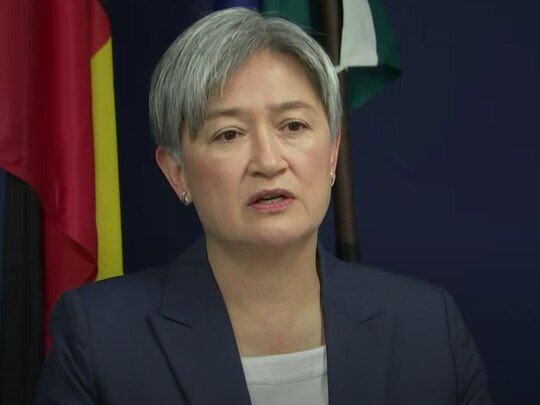 A woman with grey short hair wearing a suit.
