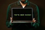 A man holding a laptop, on the screen it reads 'You've been hacked!'