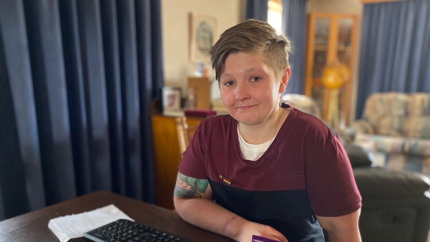 A woman sits at a table with a laptop.