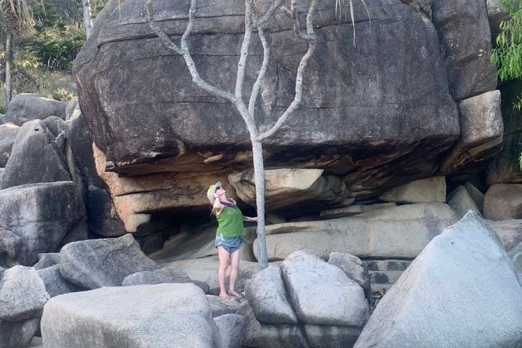 Michelle Answerth standing amongst some large rocks at a beach.