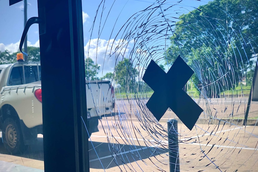 A smashed window with a cross