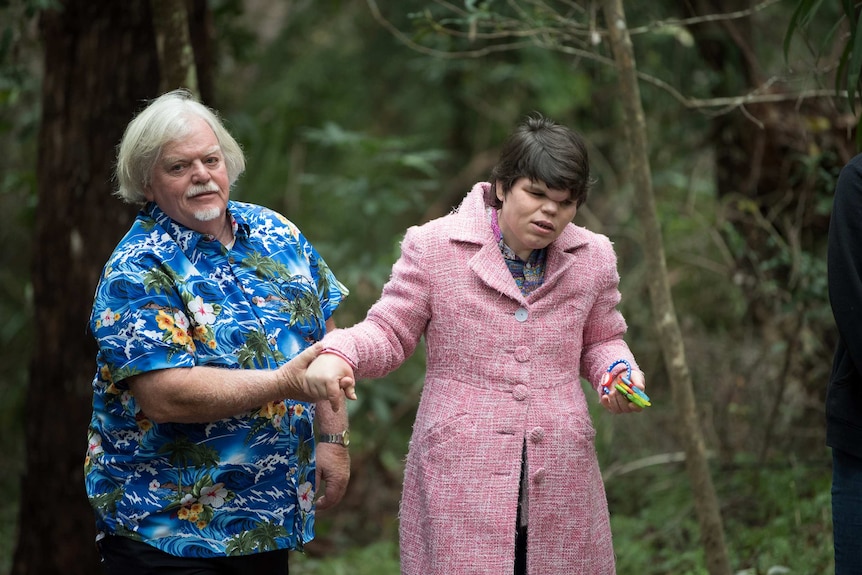 Russell wears a blue Hawaiian shirt and walks his daughter through a national park.