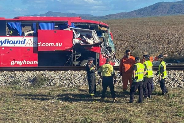 A red bus on the side of a rural highway. The front of the bus is significantly damaged.