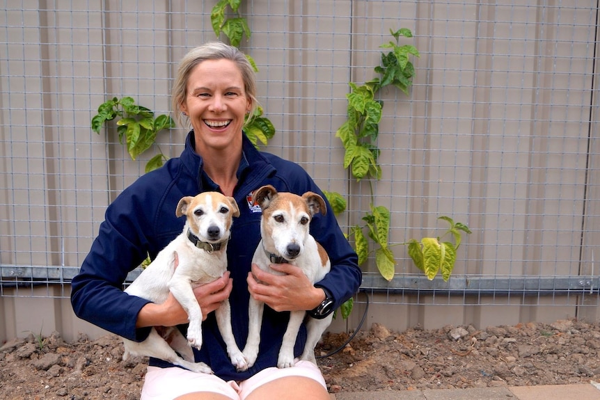 Vet Dr Louise Lehmann smiling and holding two Jack Russell dogs. 